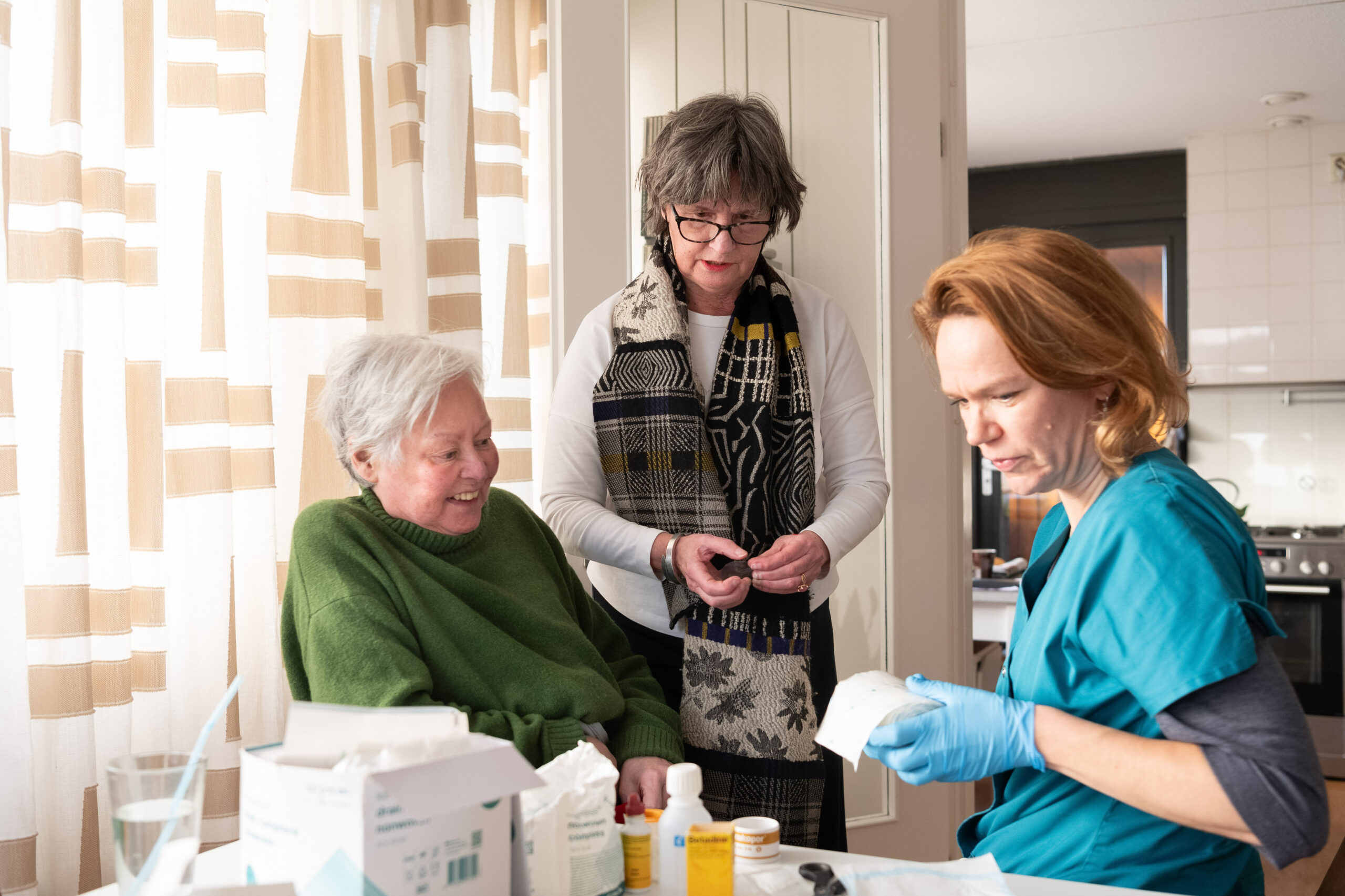 Verpleegkundige in gesprek met client en haar mantelzorger.