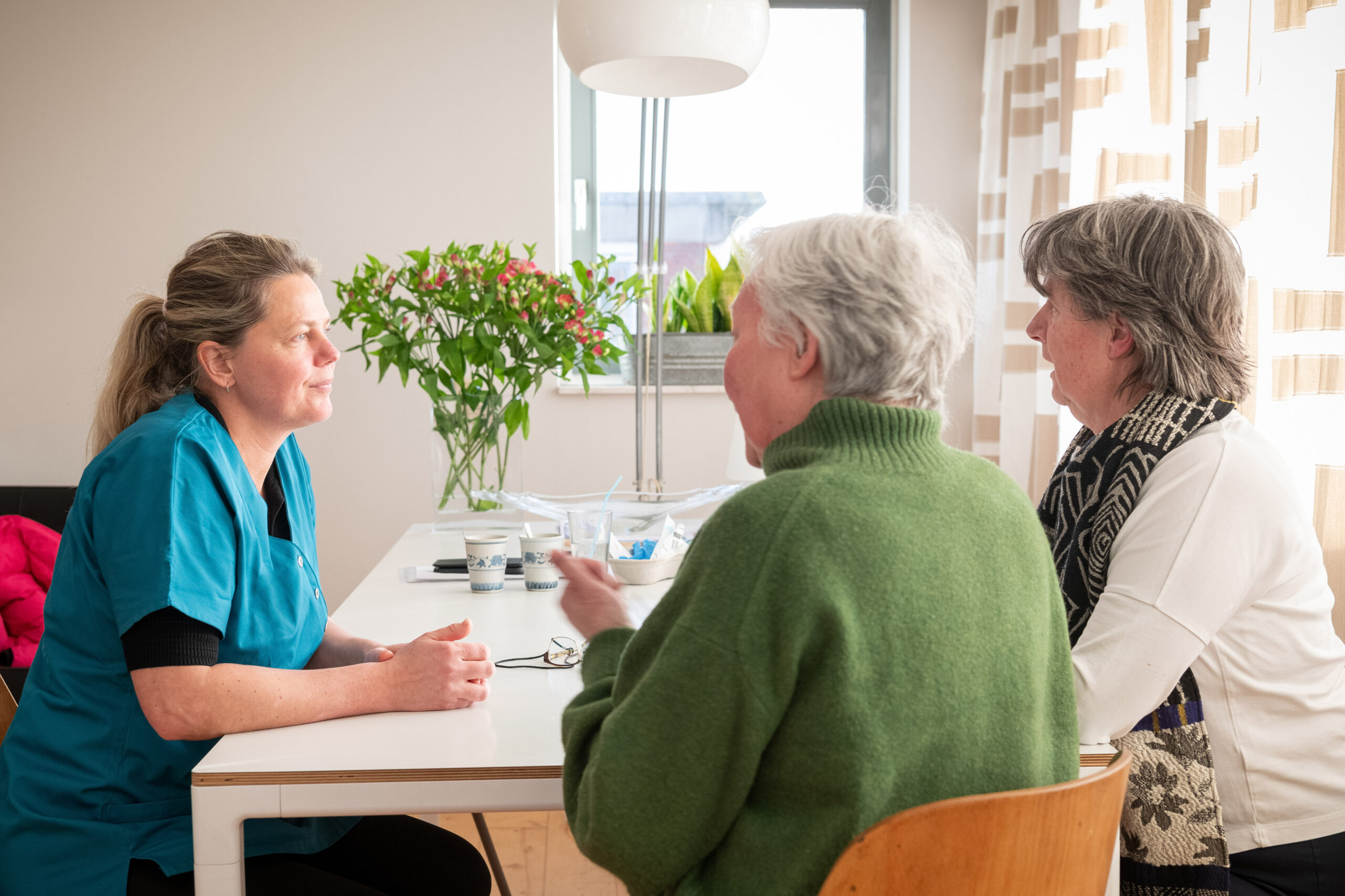 Verpleegkundige in gesprek met cliënt en mantelzorger over complementaire zorg