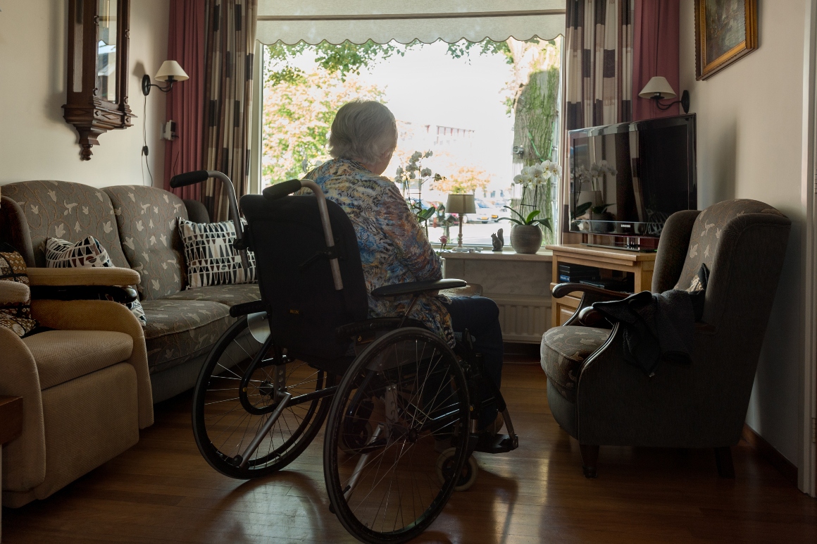 Vrouw zit thuis in een rolstoel en is misschien een zorgmijder