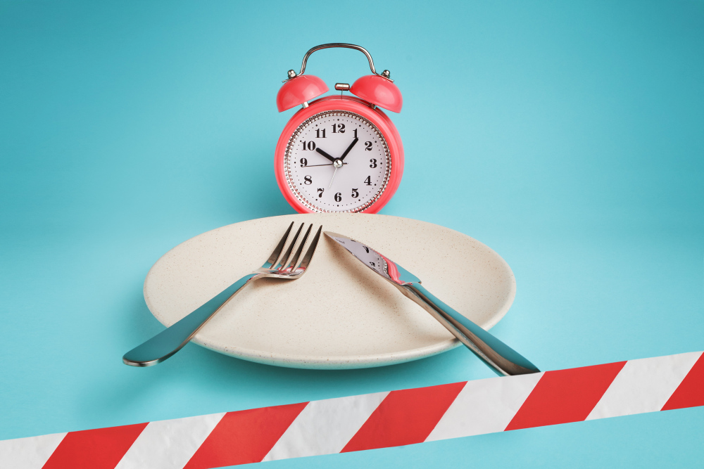 Wekker, bord met bestek, rood-wit lint. Symbool voor vasten tijdens ramadan