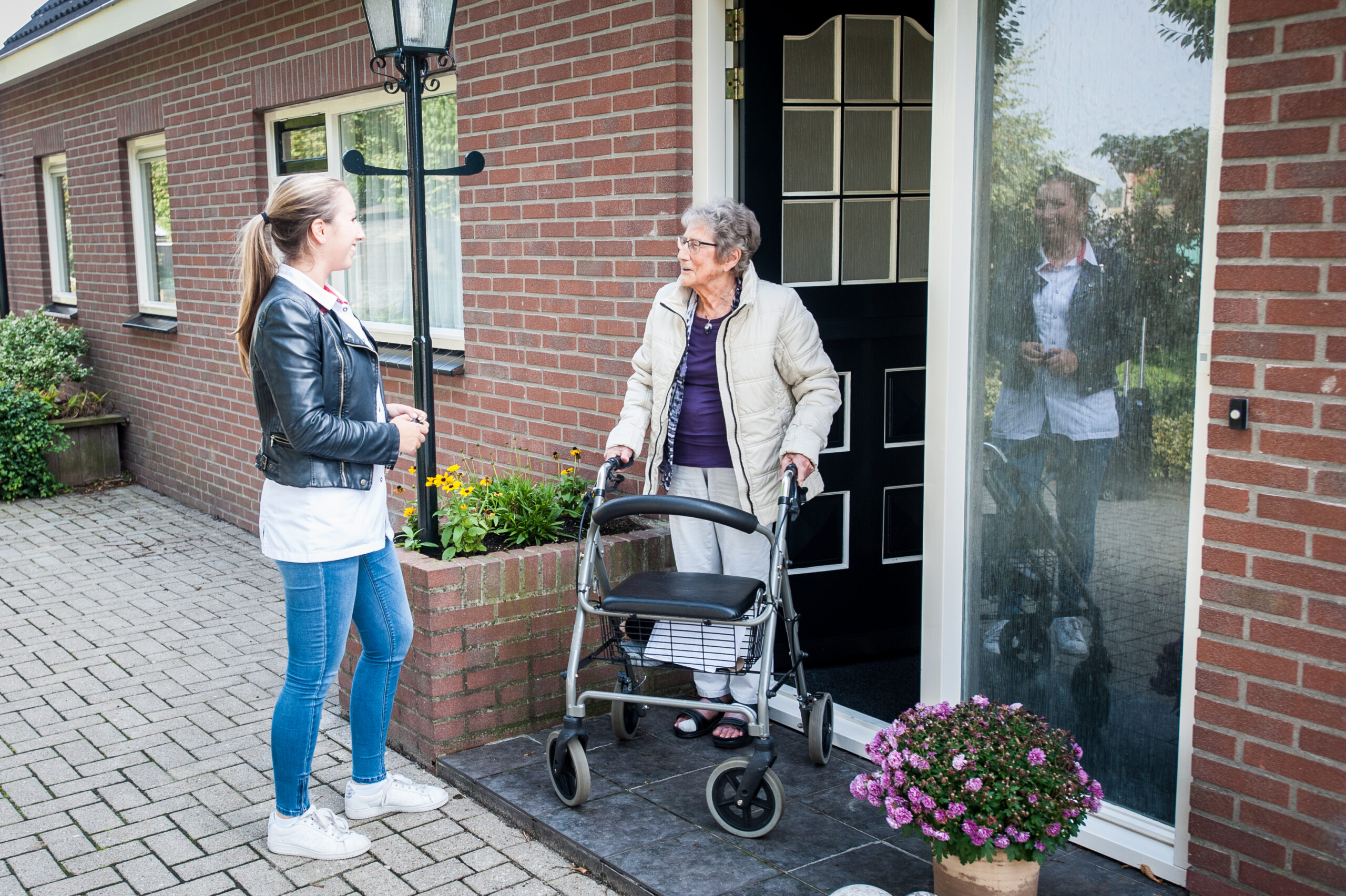 Verpleegkundige en cliënt nemen afscheid voor de deur.